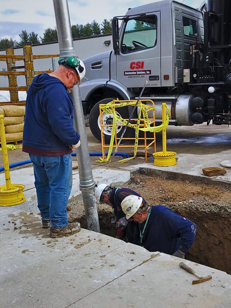 Vac truck with workers excavating in a hold with vacuum excavation in MA
