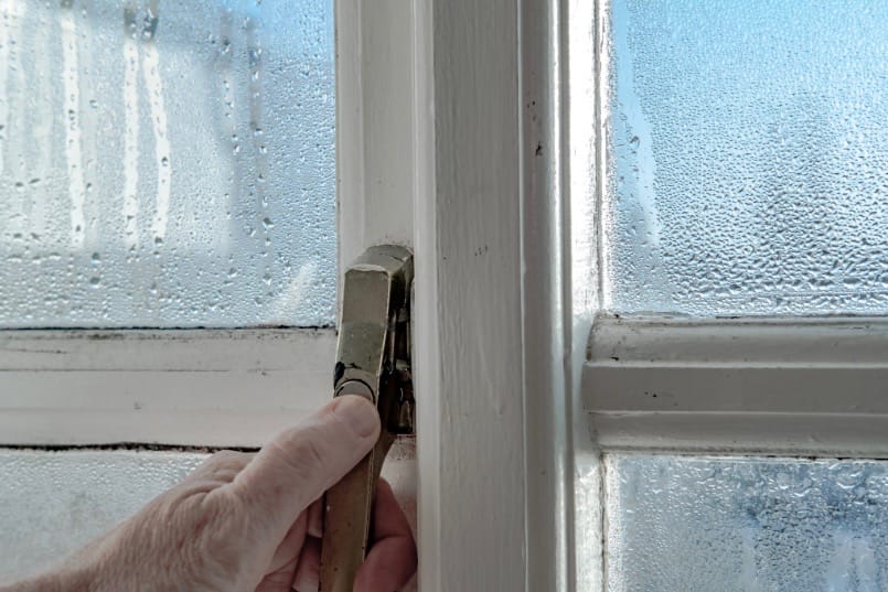 hand on door handle of a storm door showing sticking door 