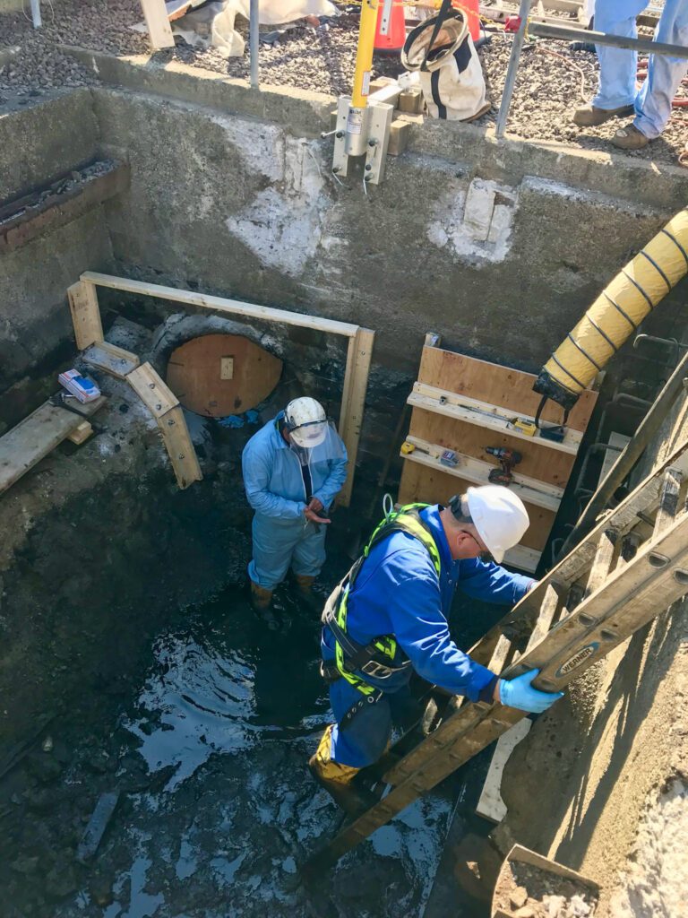 two men making a confine space entry in a utility vat for service and repair