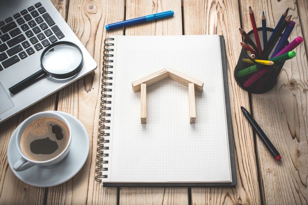 new home construction planning. Wooden frame of house on graph paper