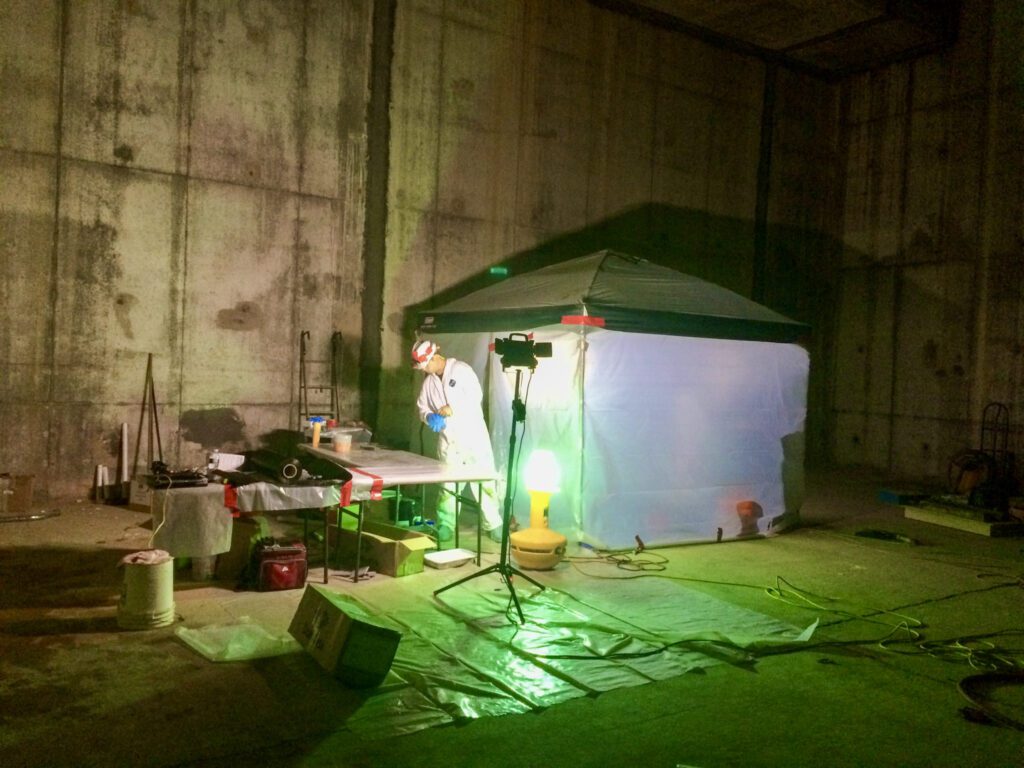 Worker in confined space underground utility system repairing pipes with a carbon fiber wrap 